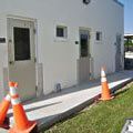 A white building with orange traffic cones in front of it.