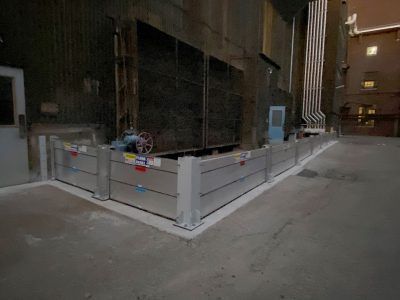 A flood barrier is sitting on the side of a street next to a building.