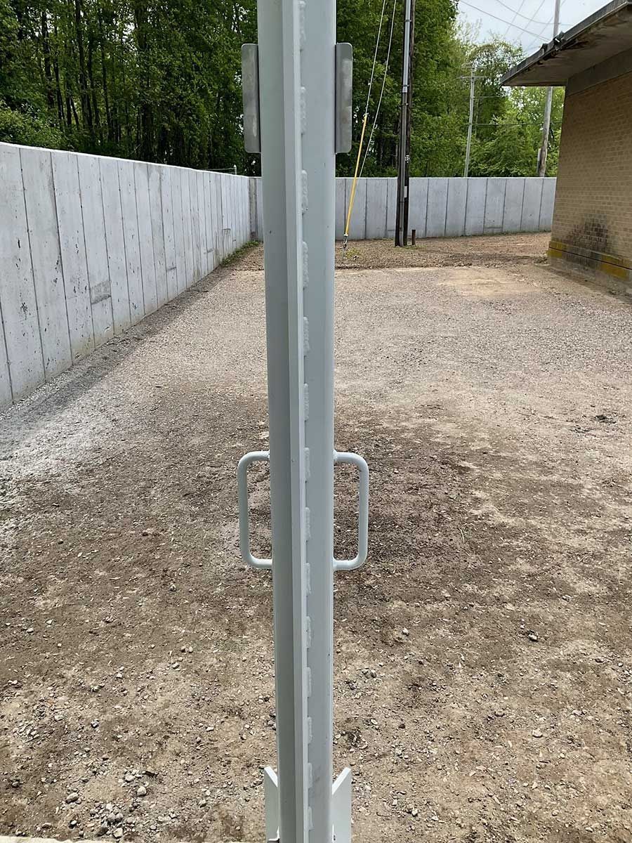 A metal pole is sitting in the middle of a dirt field.