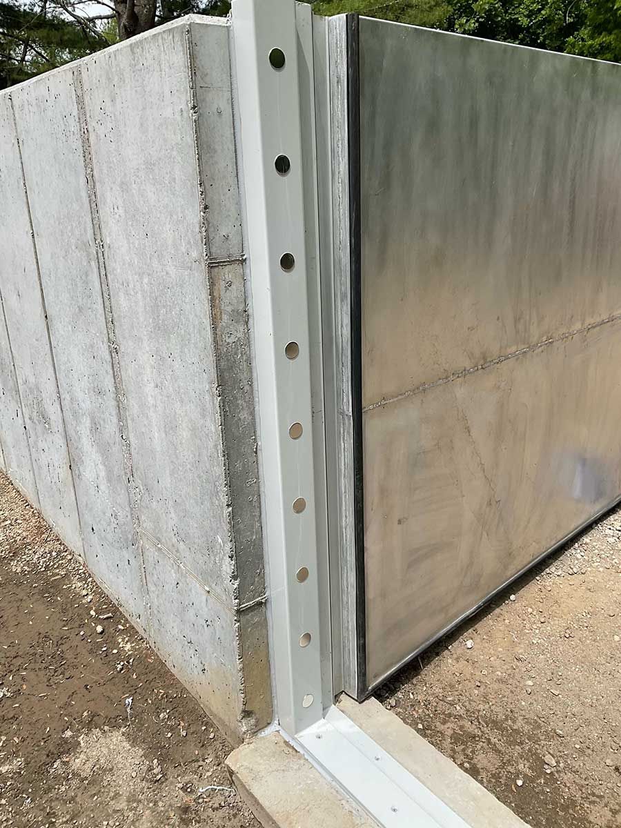 A metal fence is sitting next to a concrete wall.