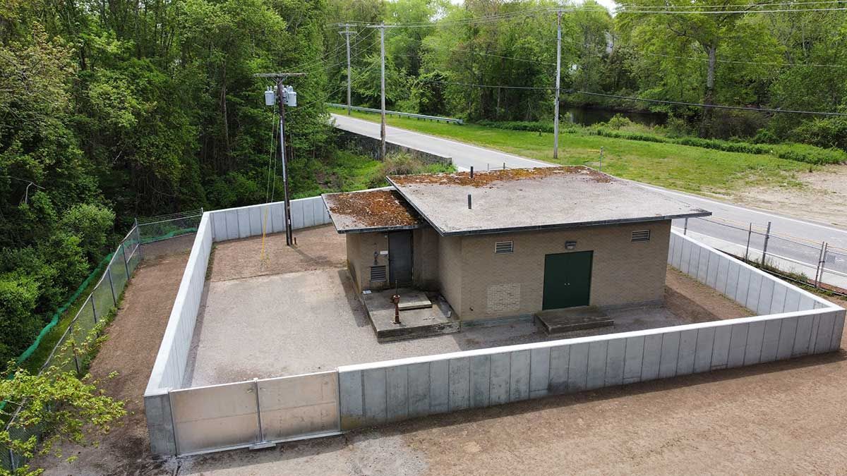 An aerial view of a small house surrounded by a fence and trees.