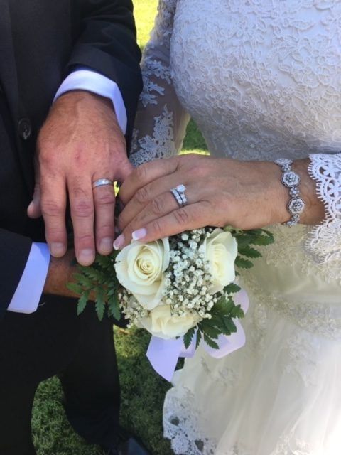A bride and groom holding hands with their wedding rings on