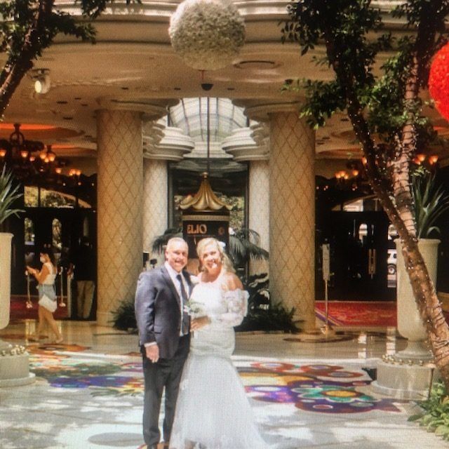 A bride and groom pose for a picture in front of a building that has the letter o on it