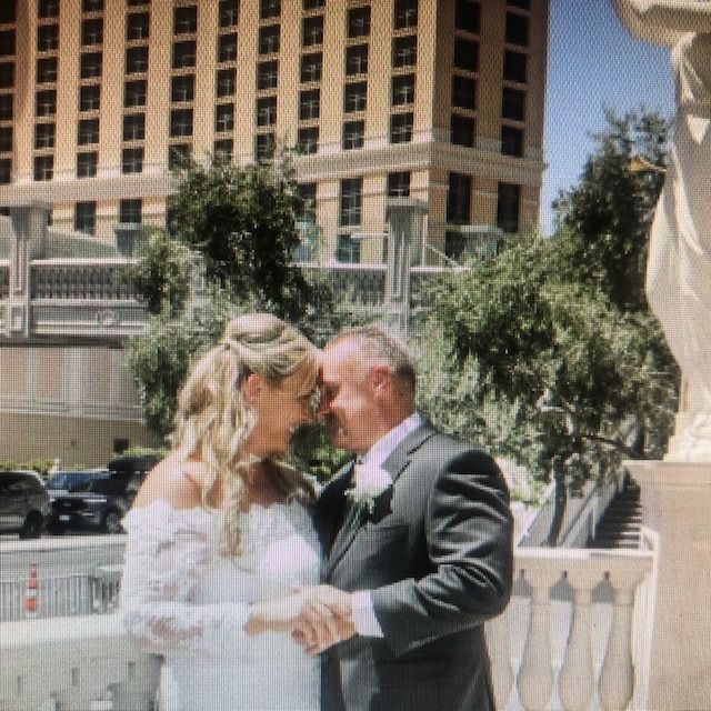 A bride and groom are kissing in front of a large building.