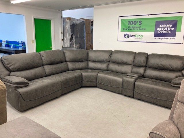 A large sectional couch is sitting in a living room next to a sign that says 100 's