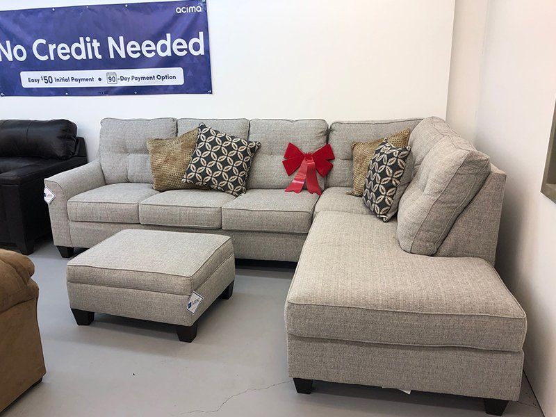A sectional couch with an ottoman and a sign that says no credit needed
