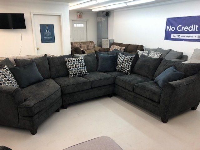 A large sectional couch is in a room with a sign that says no credit.