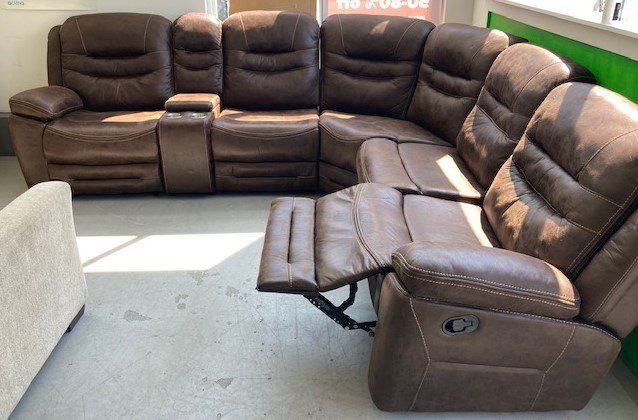 A brown leather sectional couch with a recliner in a living room.