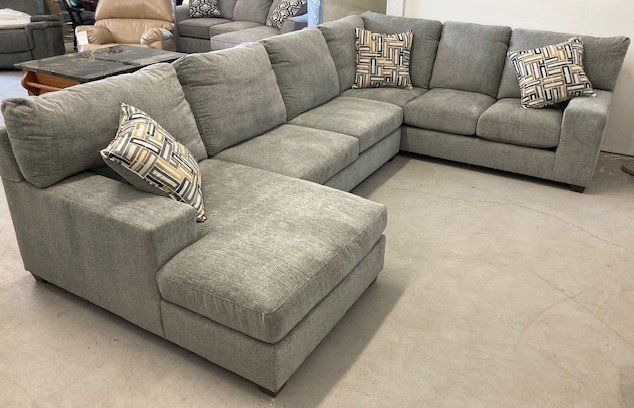 A large sectional couch is sitting on a carpet in a living room.