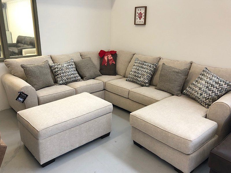 A living room with a large sectional couch and ottoman