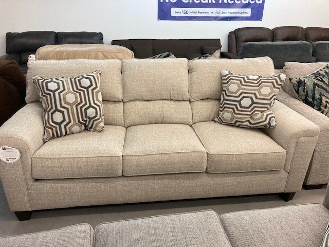 A beige couch with two pillows is sitting in a living room.