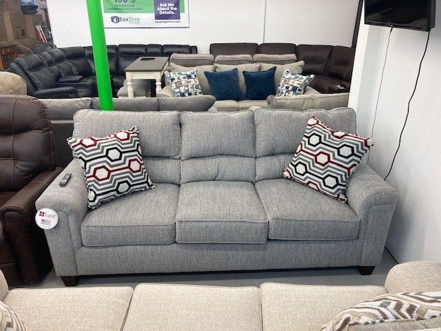 A grey couch is sitting in a living room surrounded by other furniture.