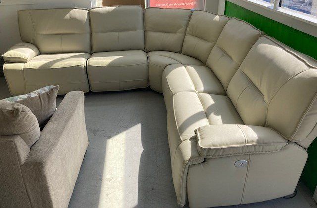 A white leather sectional couch and chair are in a living room.