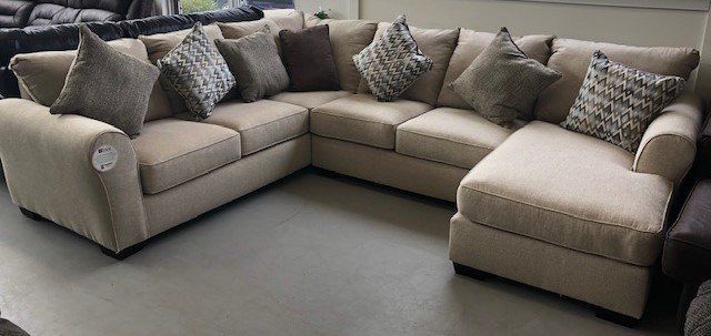 A large sectional couch with pillows on it is sitting in a living room.