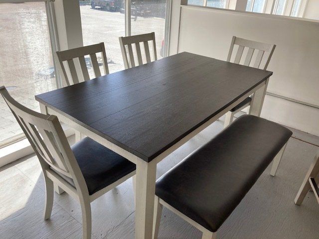 A dining table with chairs and a bench in front of a window