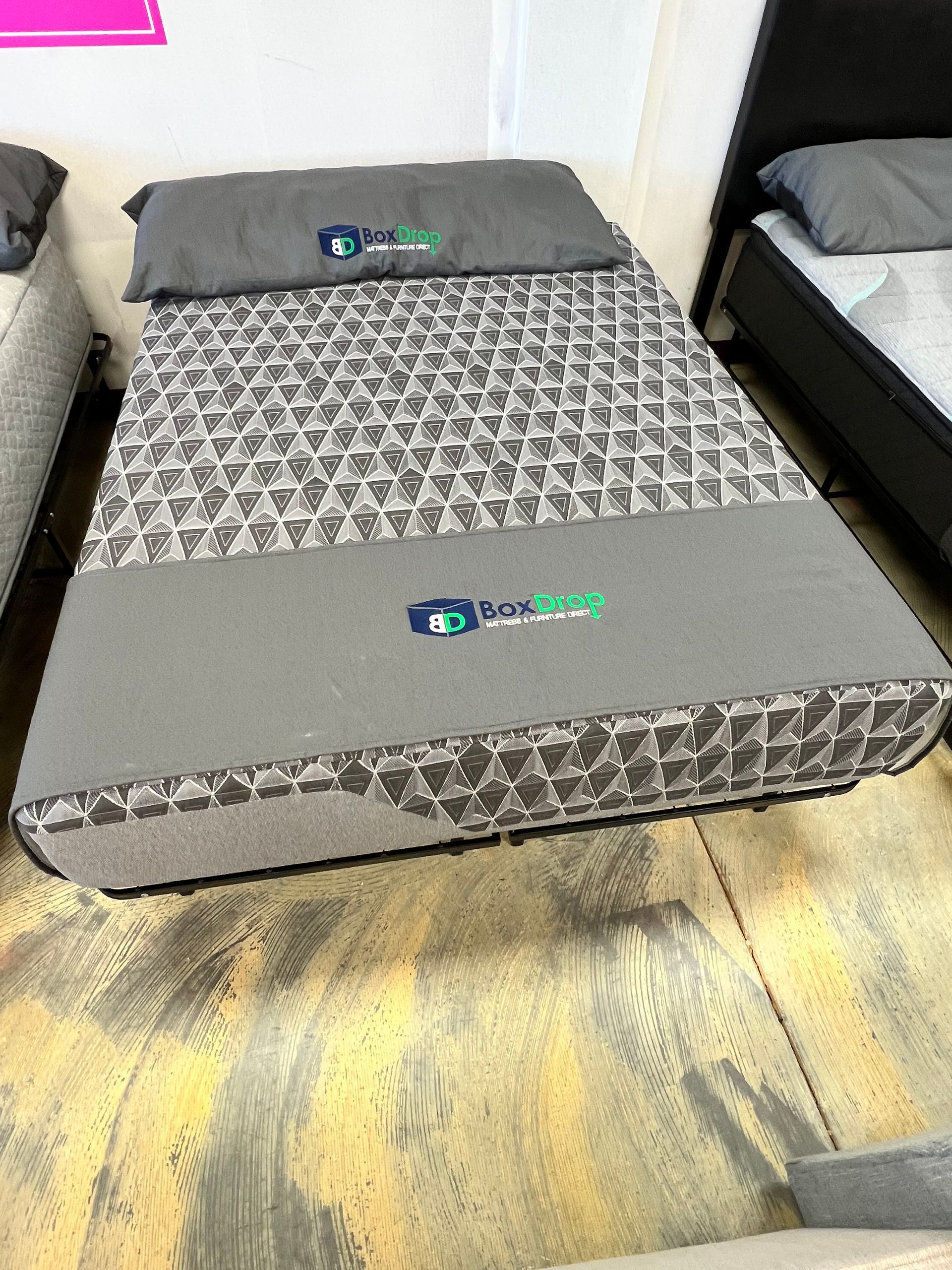 A mattress is sitting on a wooden floor next to a bed.