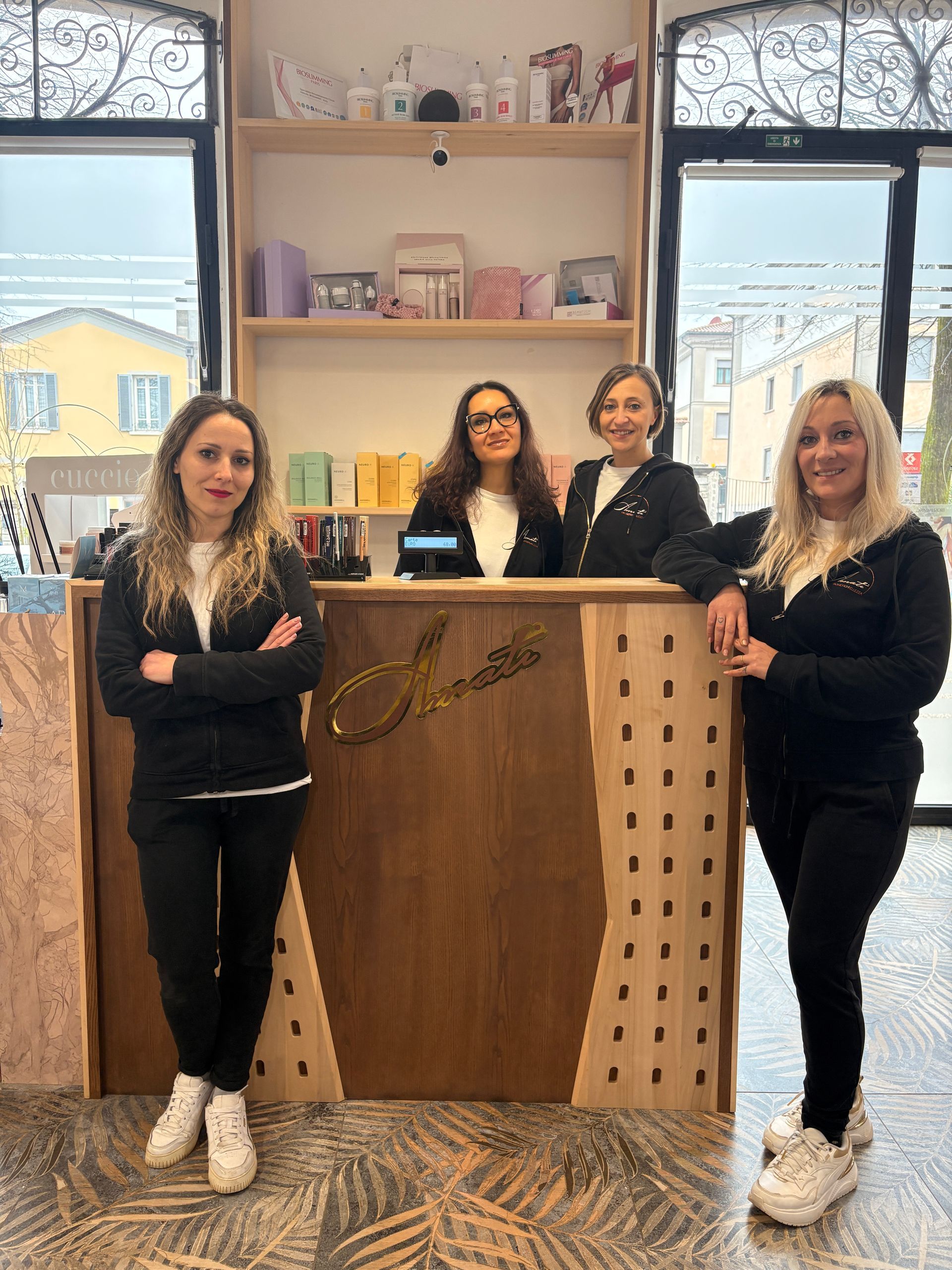 Quattro persone in piedi su e vicino a una scala in un interno moderno e luminoso, sorridono alla macchina fotografica.