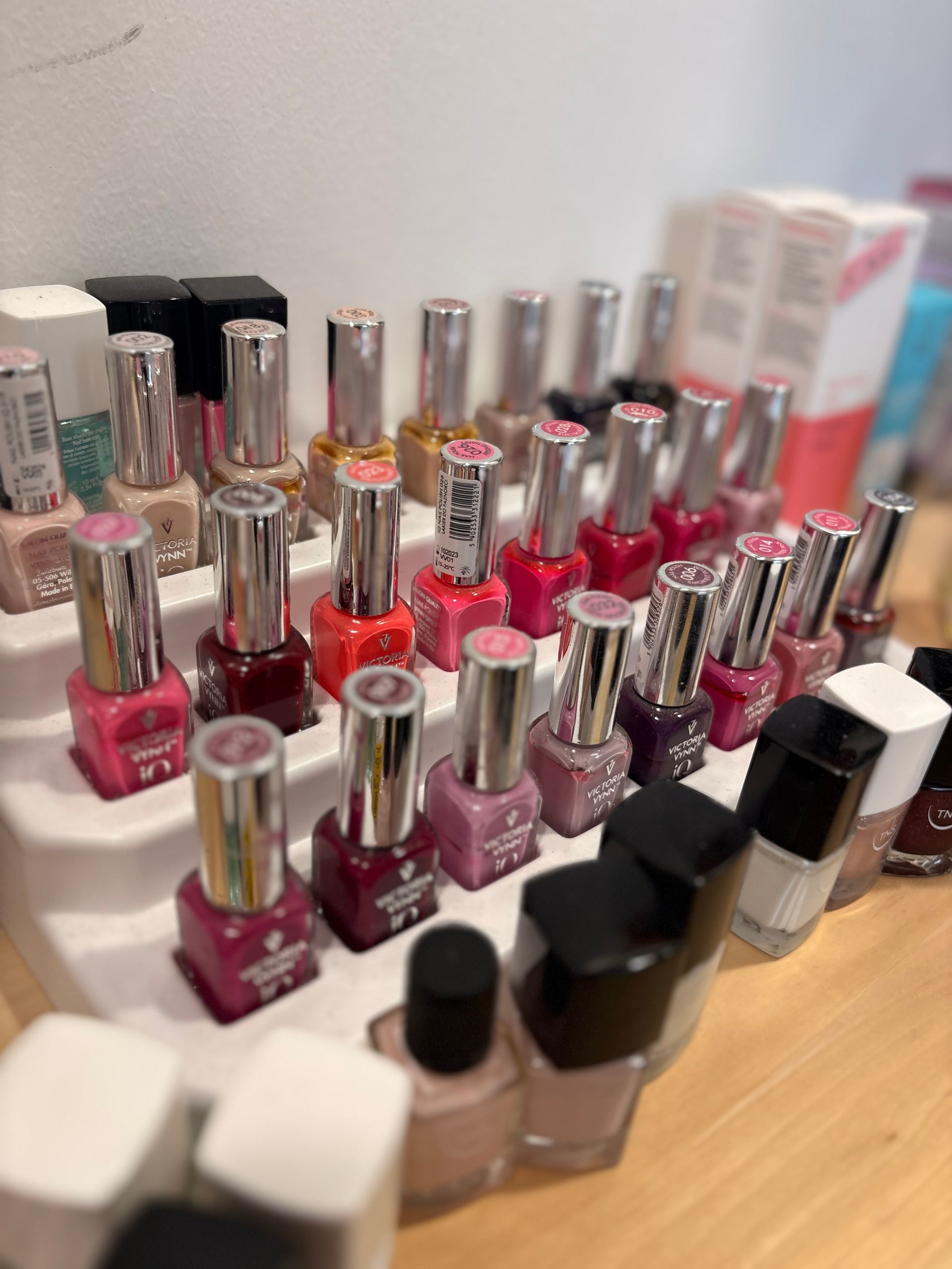 Primo piano di mani con unghie curate color rosa corallo e strisce di glitter argentato su alcune unghie.