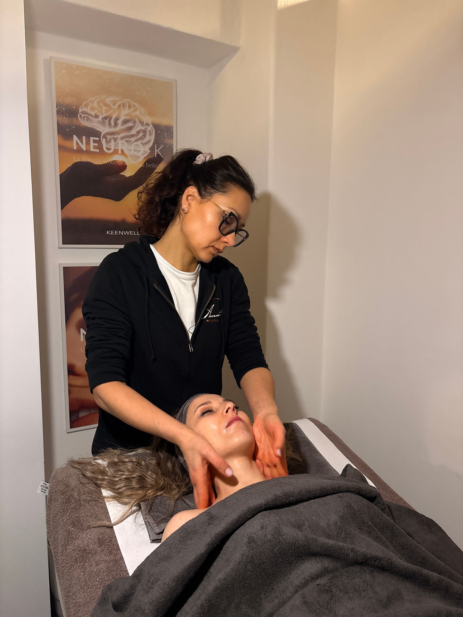 Un'estetista professionista con guanti rosa utilizza un dispositivo per microneedling sulla guancia di una persona durante un trattamento cutaneo.