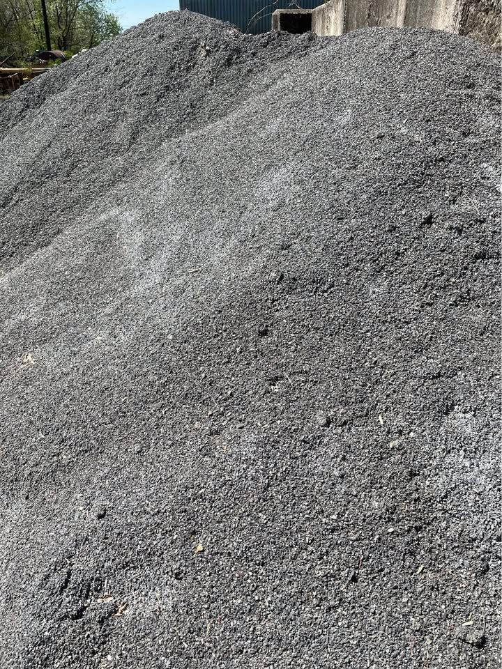 Large pile of dark gray gravel in an outdoor setting.