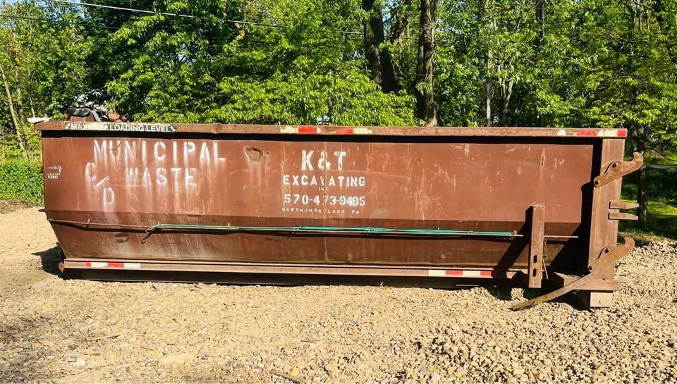 Brown dumpster on gravel.