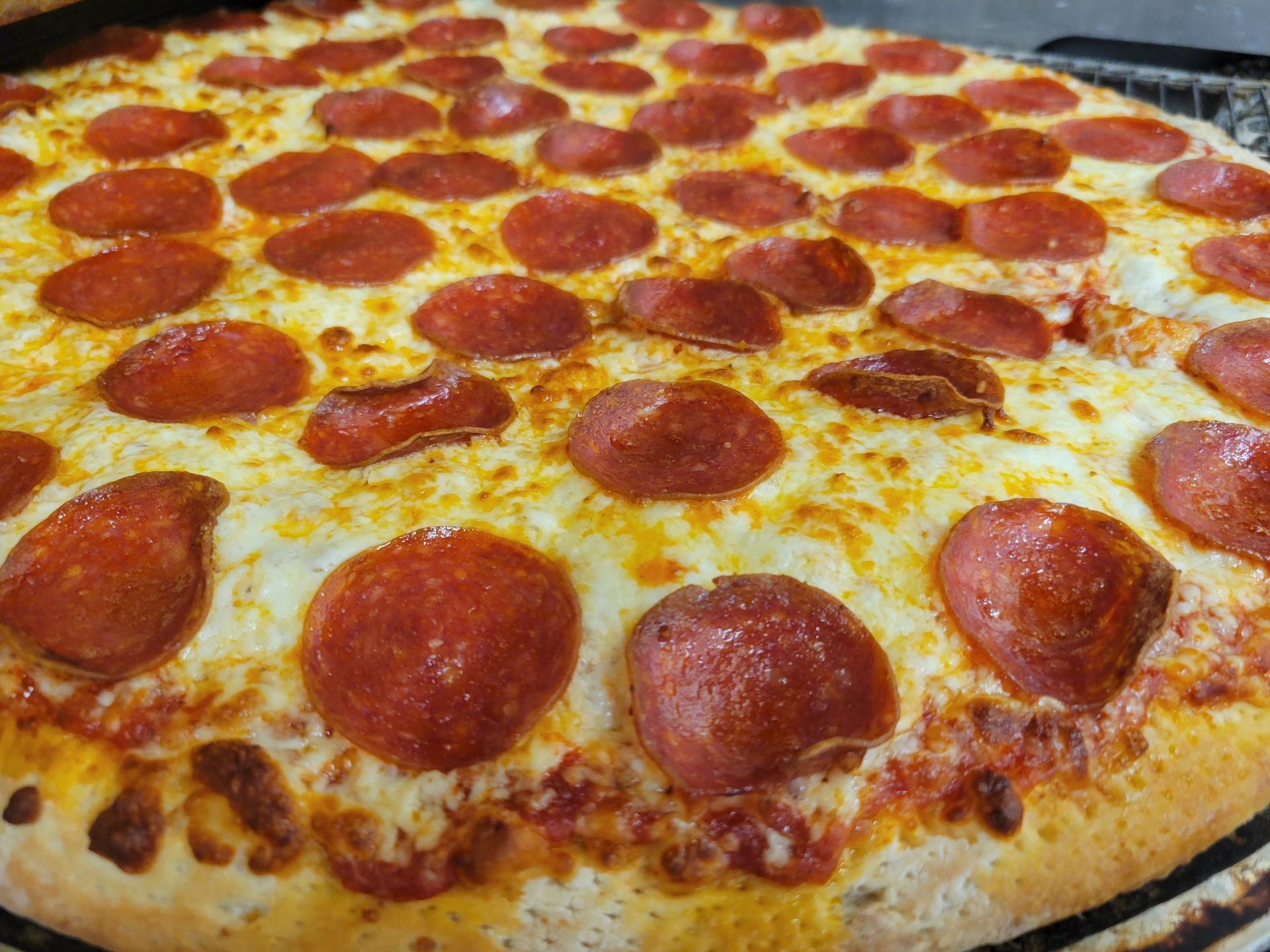 Pepperoni pizza with melted cheese, a golden crust, and a dark background.