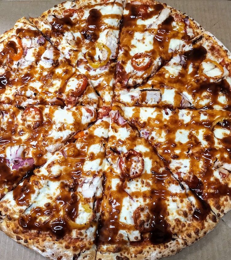 Barbecue chicken pizza, sliced, with sauce and cheese.