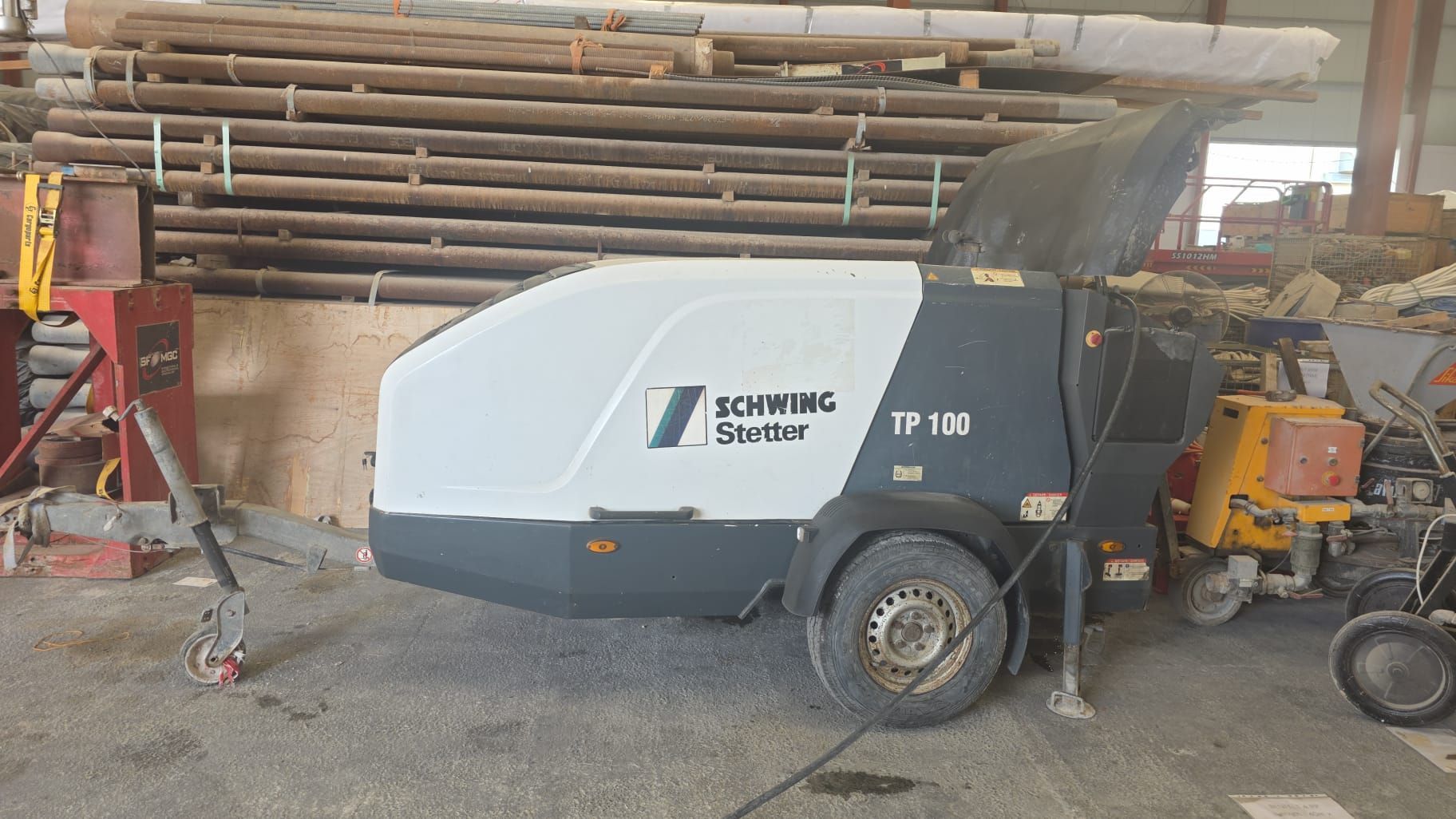 White and gray Schwing TP 150 concrete pump on a construction site.