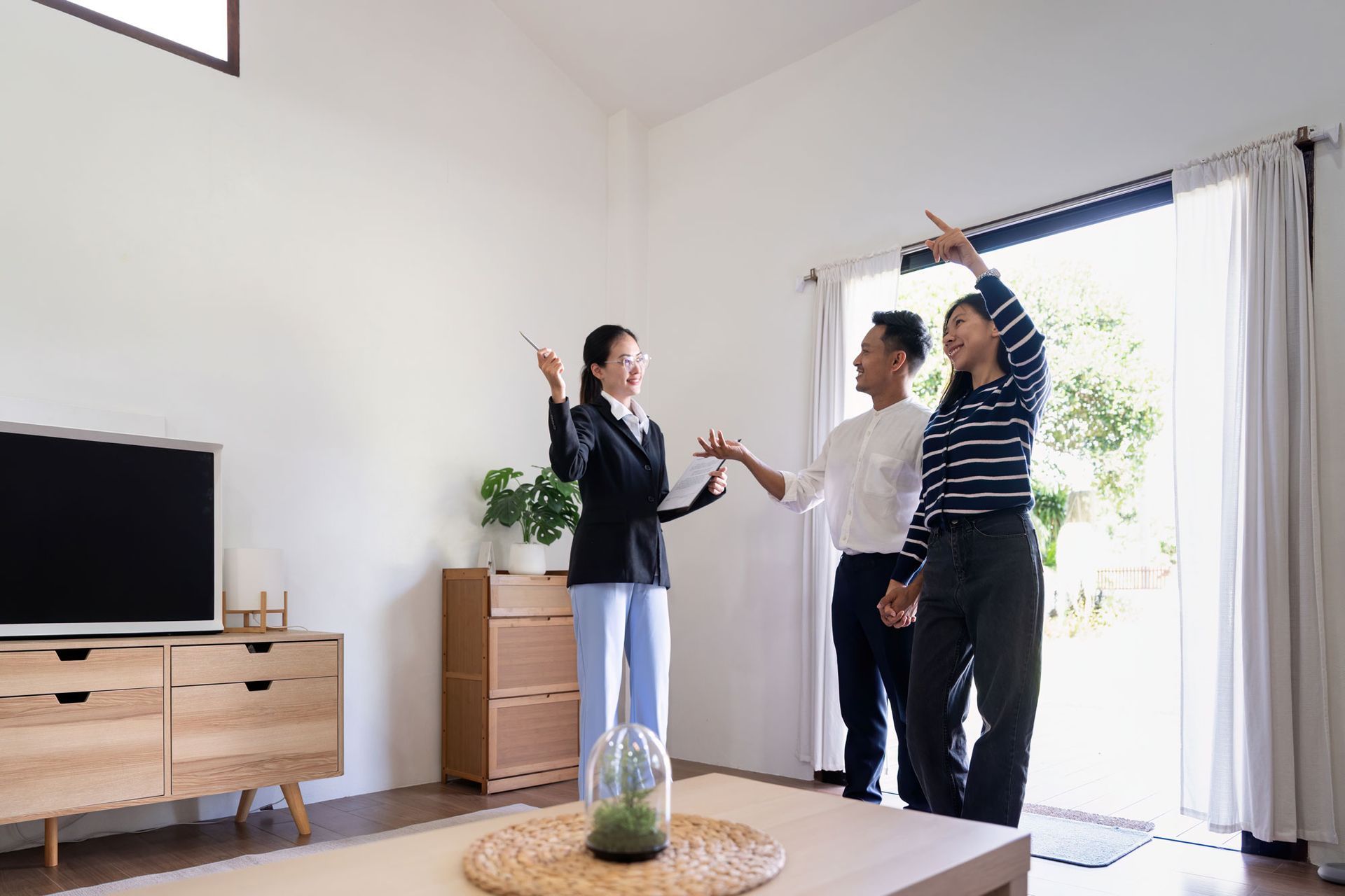 A group of people are standing in a living room looking at a house.