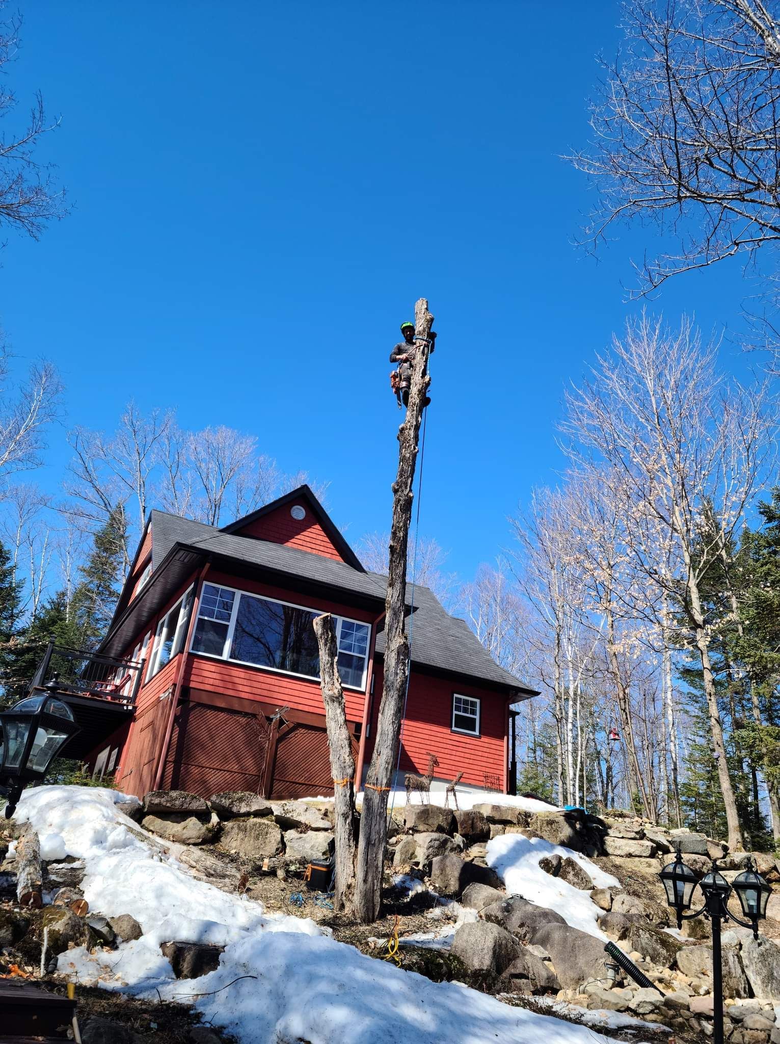 Une maison rouge est assise au sommet d'une colline couverte de neige dans les bois.