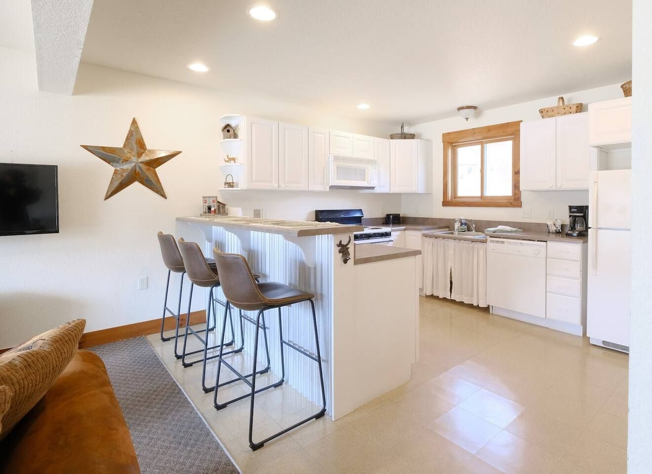 Kitchen with white cabinets, breakfast bar with stools, and a star decoration on the wall.