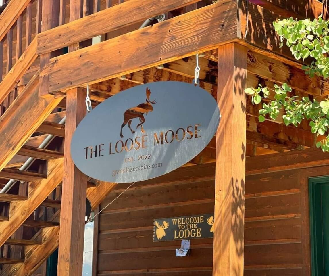 Oval sign for "The Loose Moose Lodge" with moose silhouette, hanging from a wooden building.