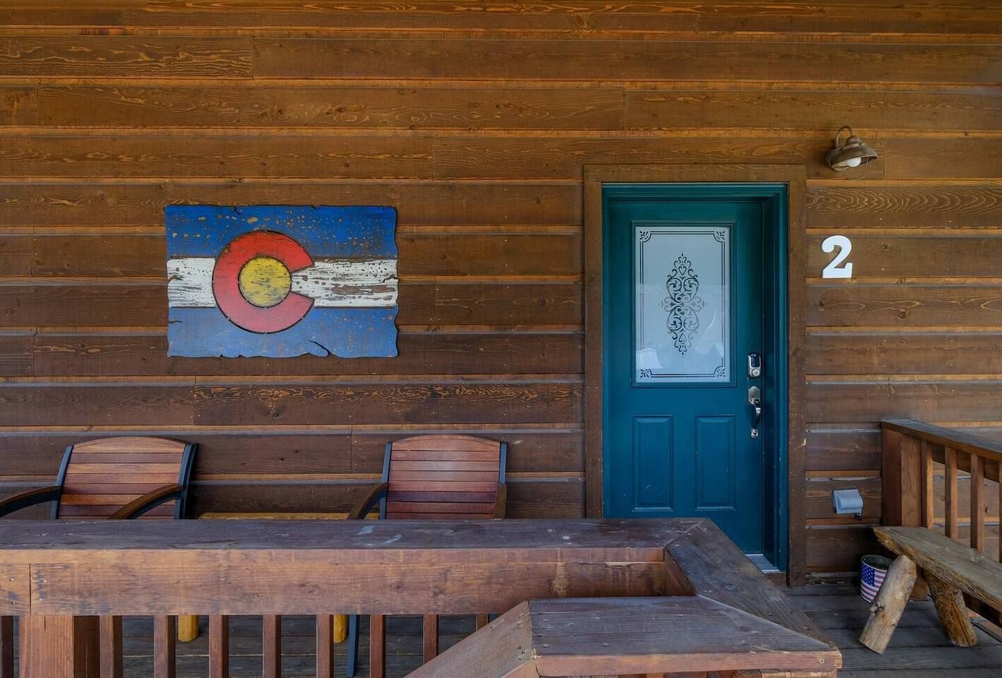 Wooden cabin exterior with Colorado flag, blue door, and the number "2."