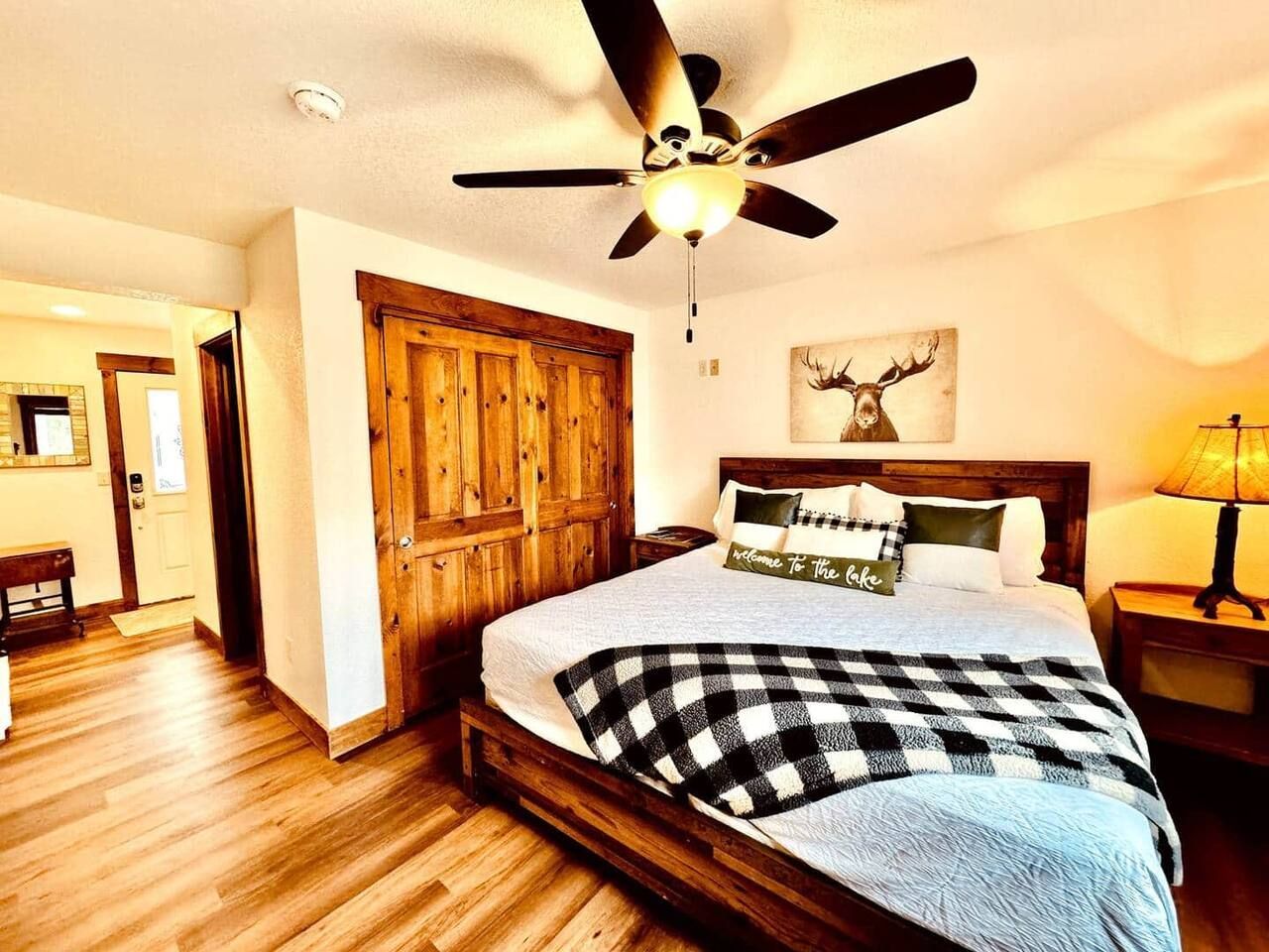 Bedroom with wood floors, bed, rustic closet doors, and a deer art piece.