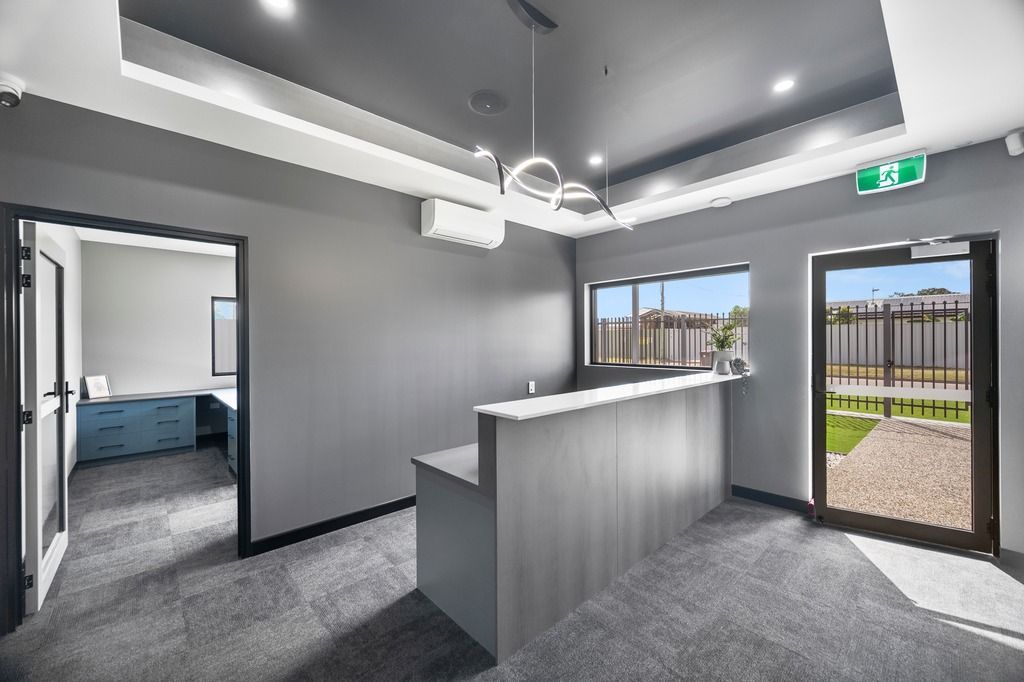 Gray office reception area with a desk, entrance, and window — Construction Company in Townsville, QLD