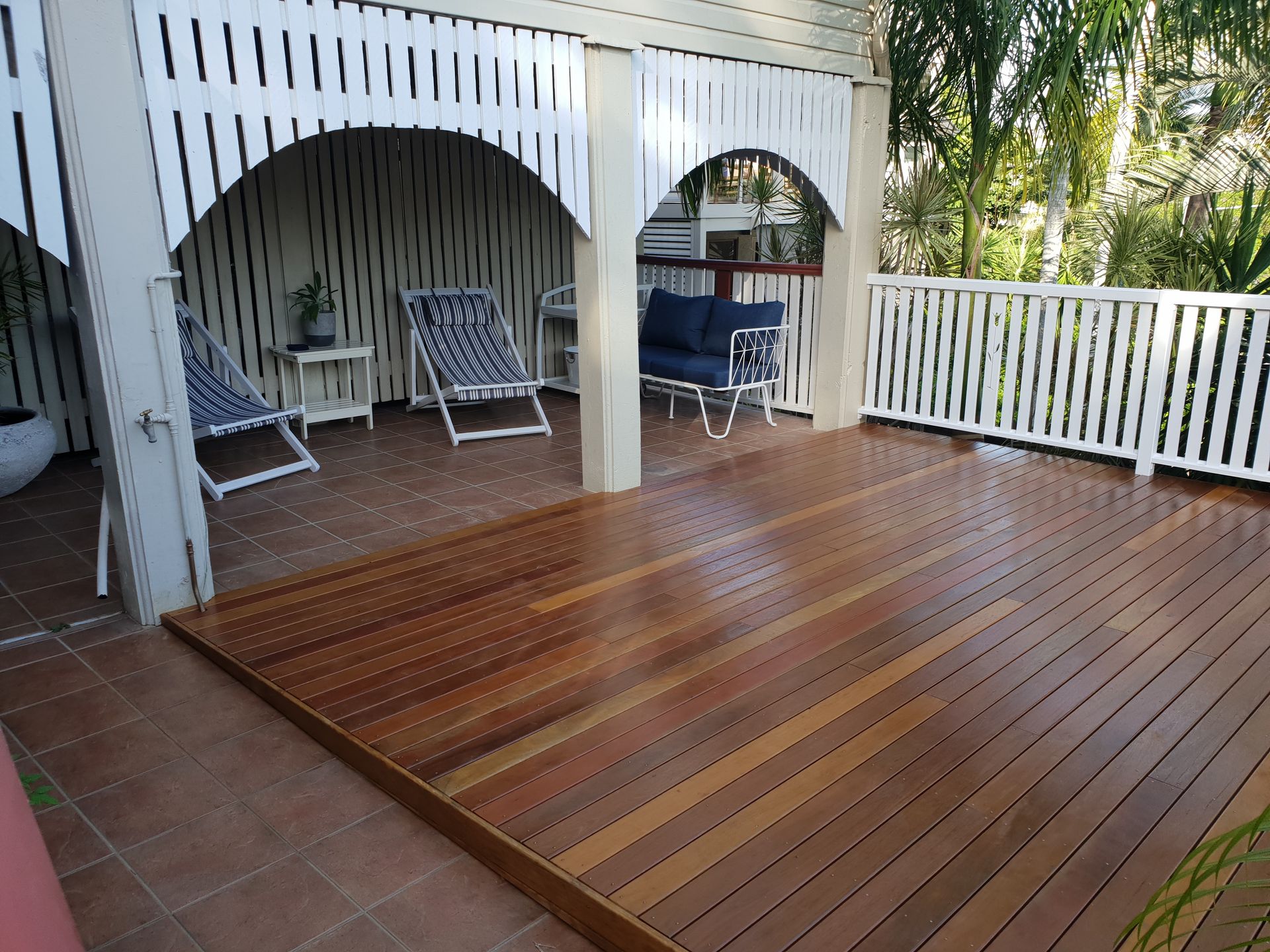 Wooden deck with chairs, under a white veranda with a railing — Construction Company in Townsville, QLD