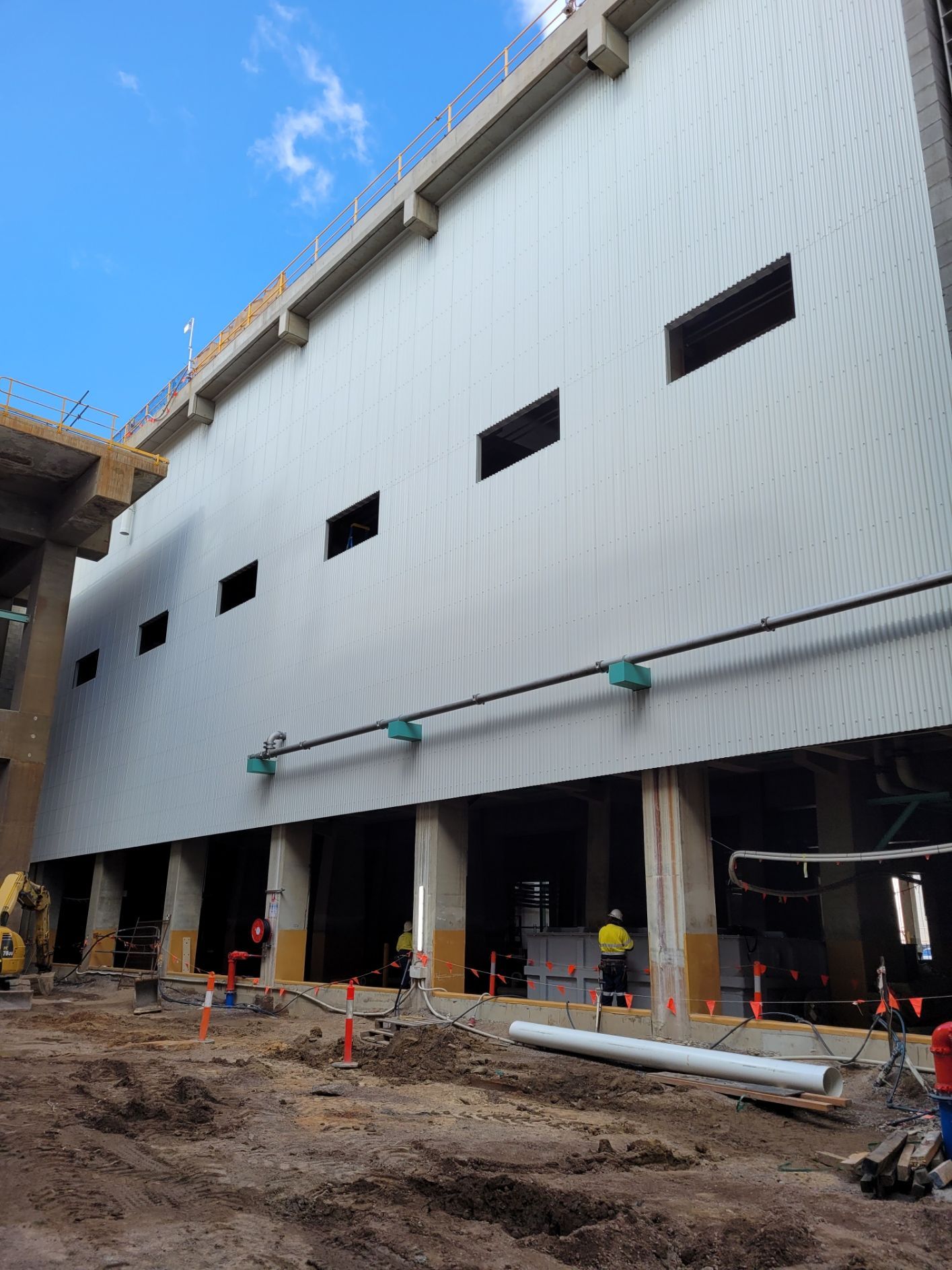 Construction site with a tall, light-colored building and workers — Construction Company in Townsville, QLD