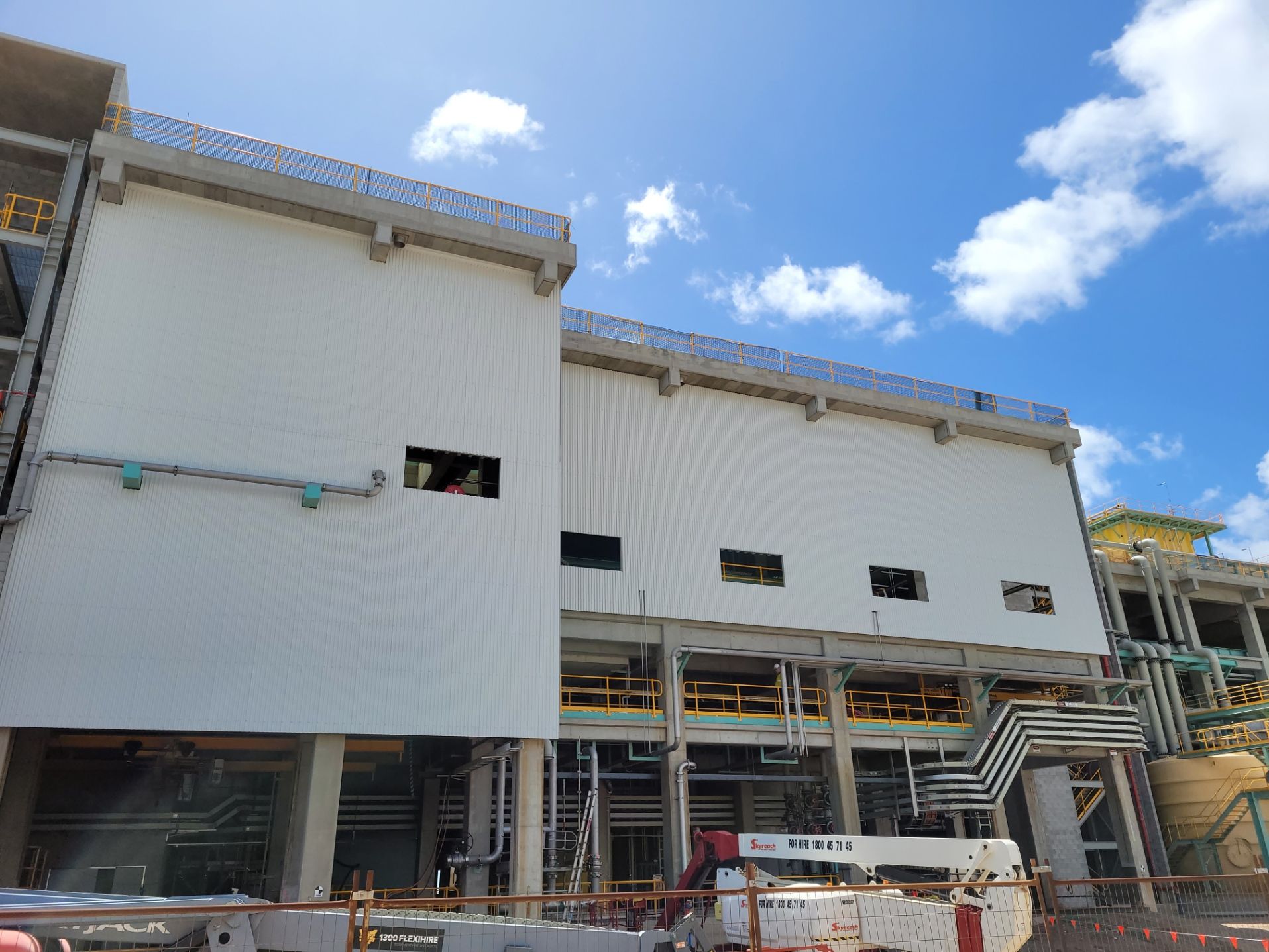 Construction of a white industrial building with metal siding, pipes, and sky above — Construction Company in Townsville, QLD