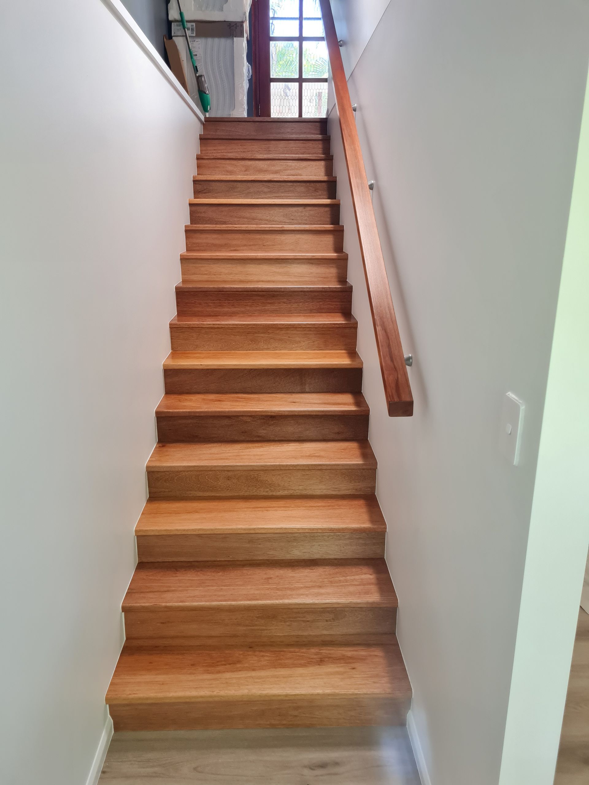 Wooden staircase leading upwards, with a wooden handrail on the right — Construction Company in Townsville, QLD