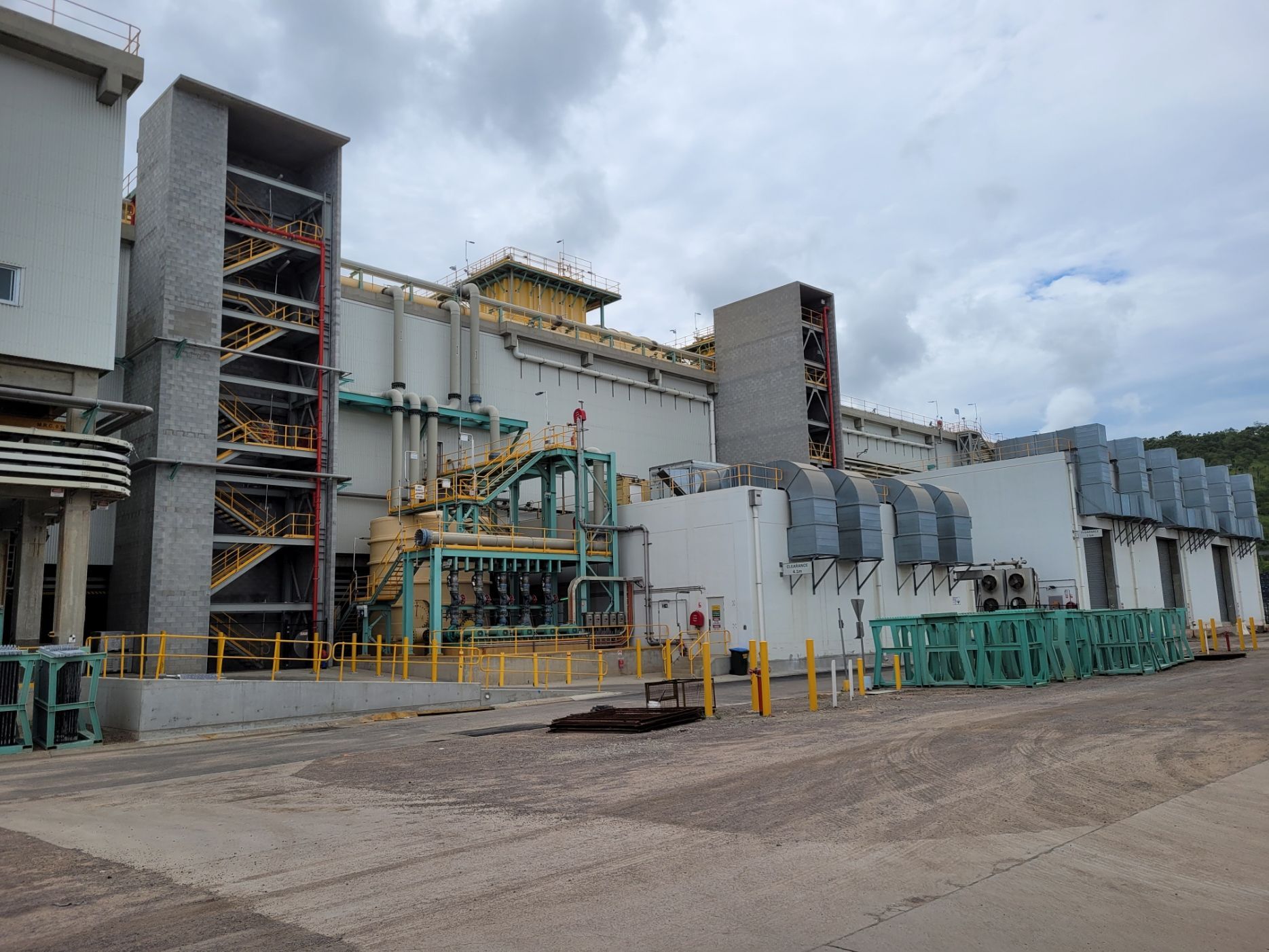 Industrial building exterior with pipes, vents, and metal structures, gray and beige, against a cloudy sky — Construction Company in Townsville, QLD