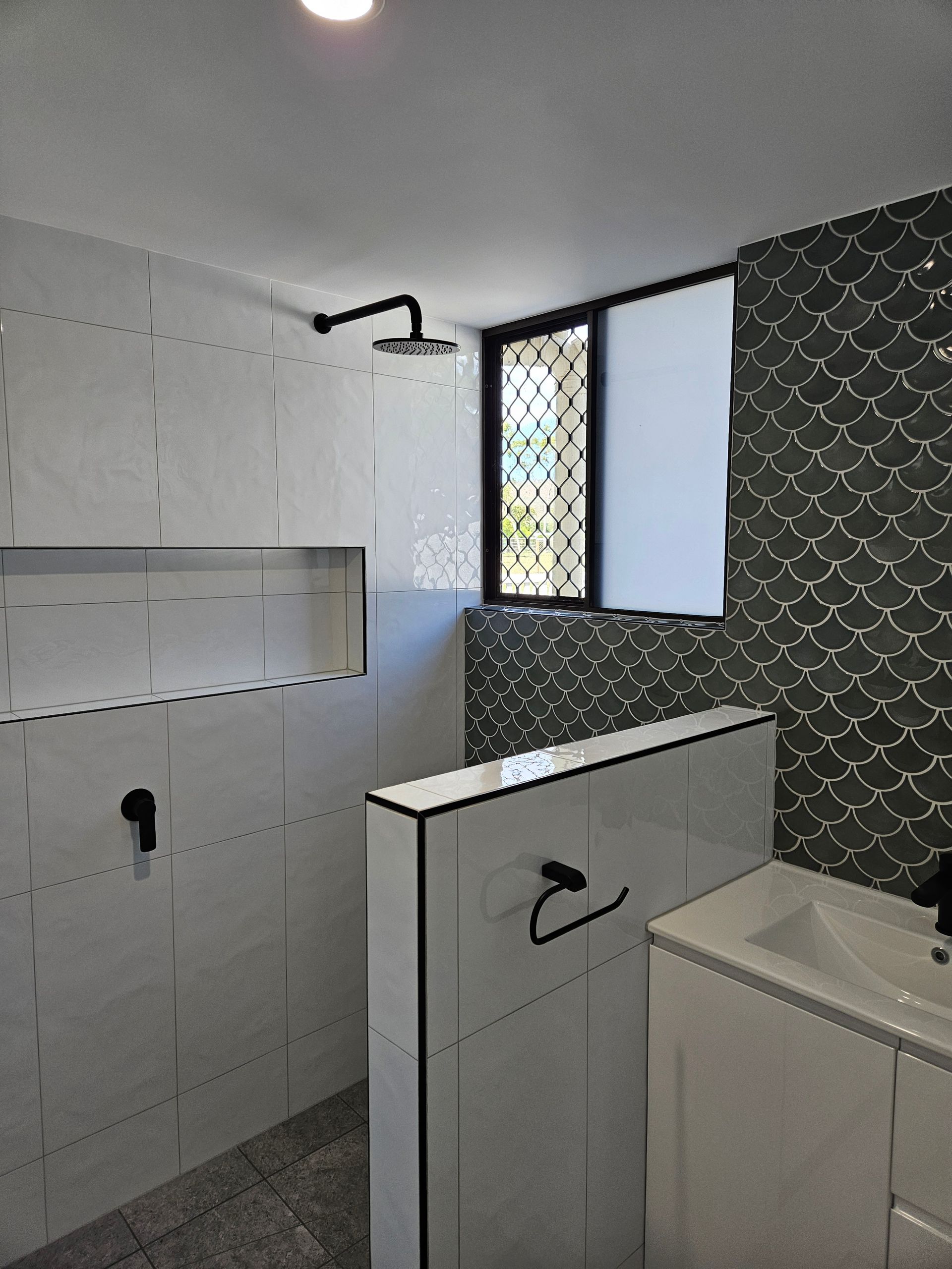 Modern bathroom with shower and black fixtures, white and dark gray tiles — Construction Company in Townsville, QLD