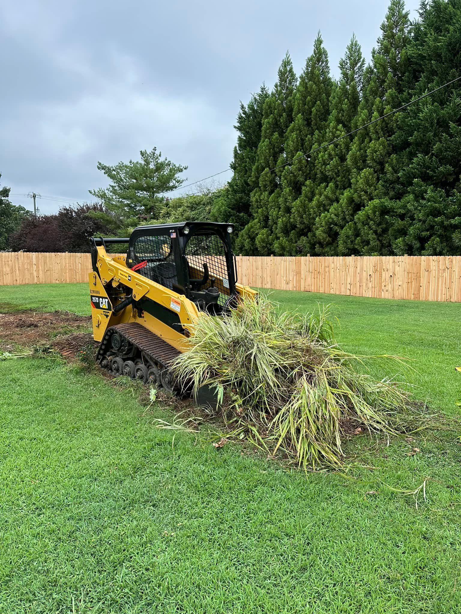 A yellow bulldozer is cutting grass in a lush green field.
