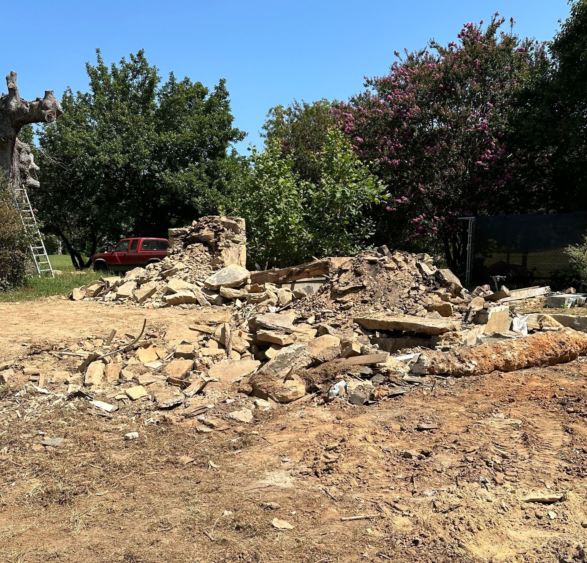 A pile of rubble in a field with trees in the background