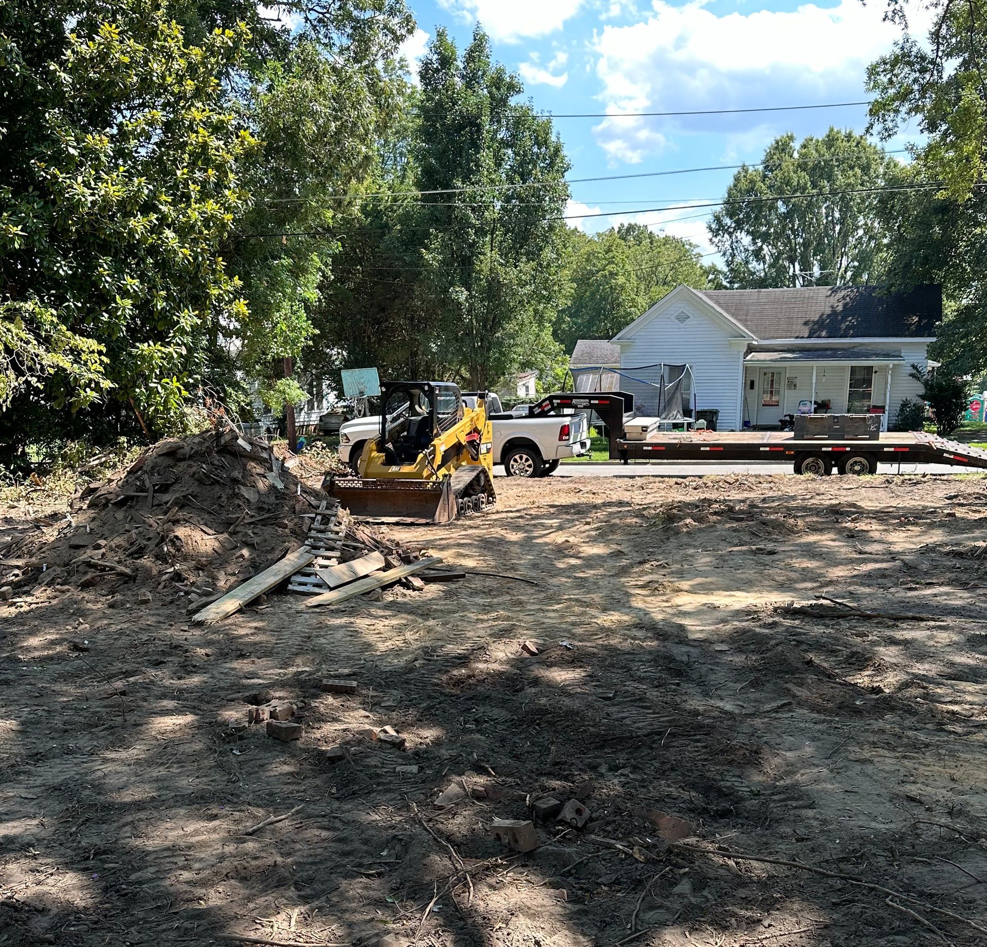 A bulldozer is digging a hole in the dirt in front of a house.
