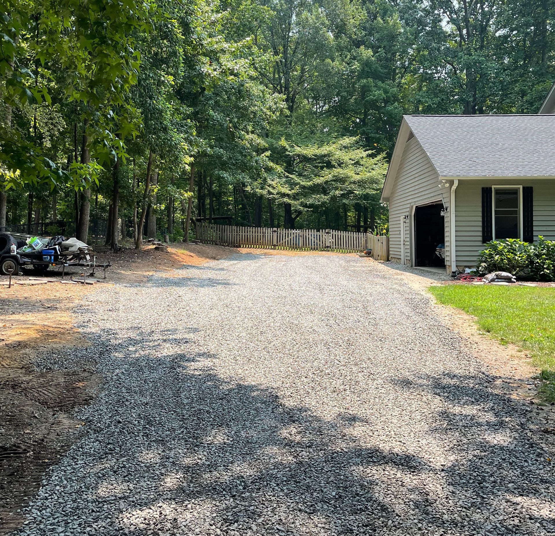 A gravel driveway leading to a house in the woods.