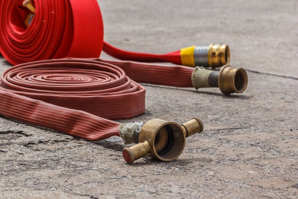 Two fire hoses are laying on the ground next to each other — Fireline 2000 Fire Equipment Pty Ltd in Browns Plain, QLD