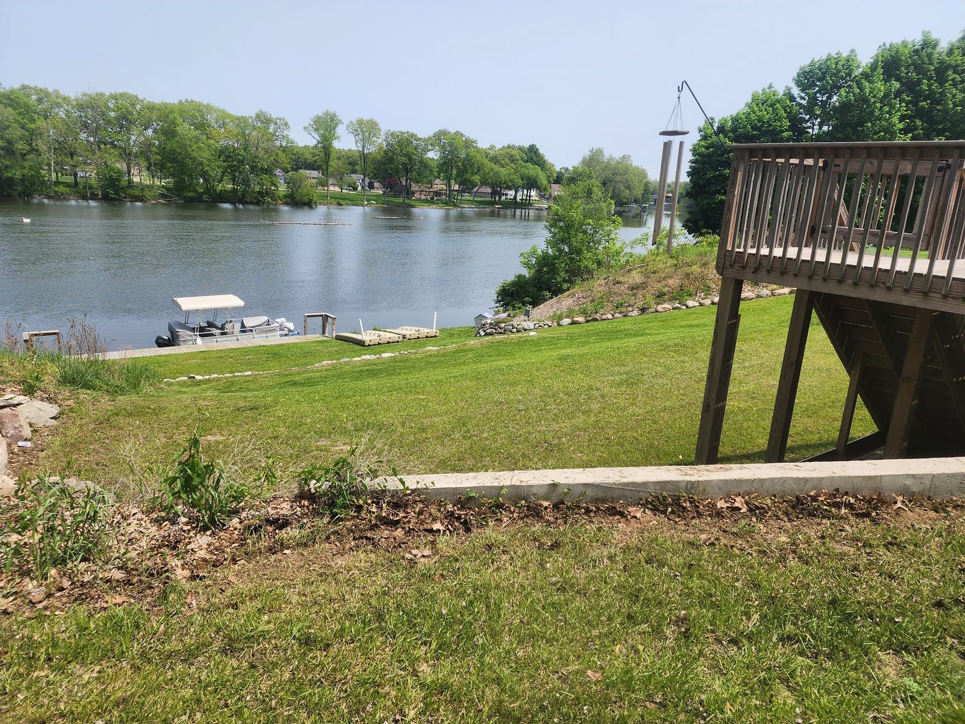 Lakeside park with grassy hill, dock by the water, and a wooden deck overlooking the river