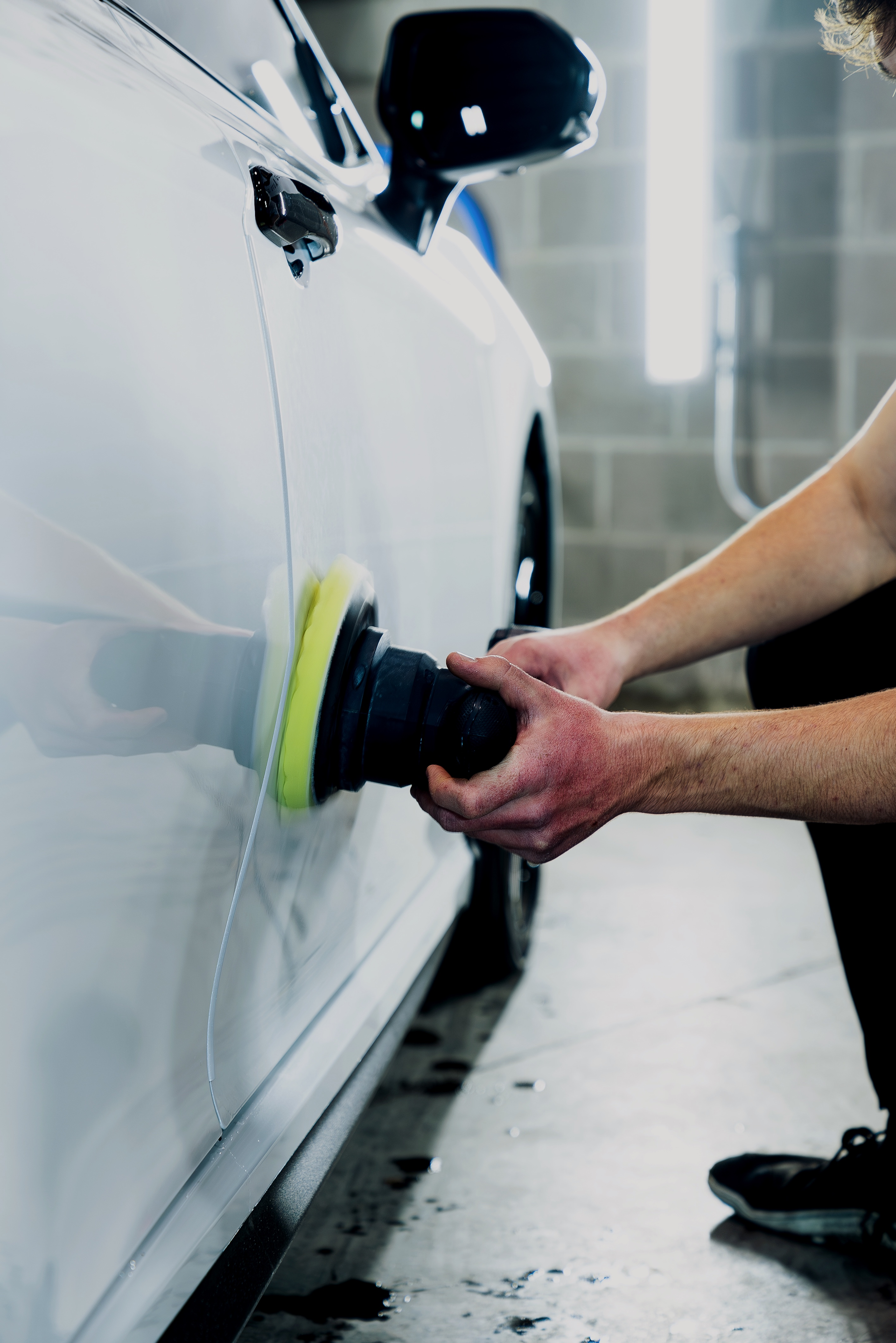 A gloved hand using a red detail brush to clean a car's center console.