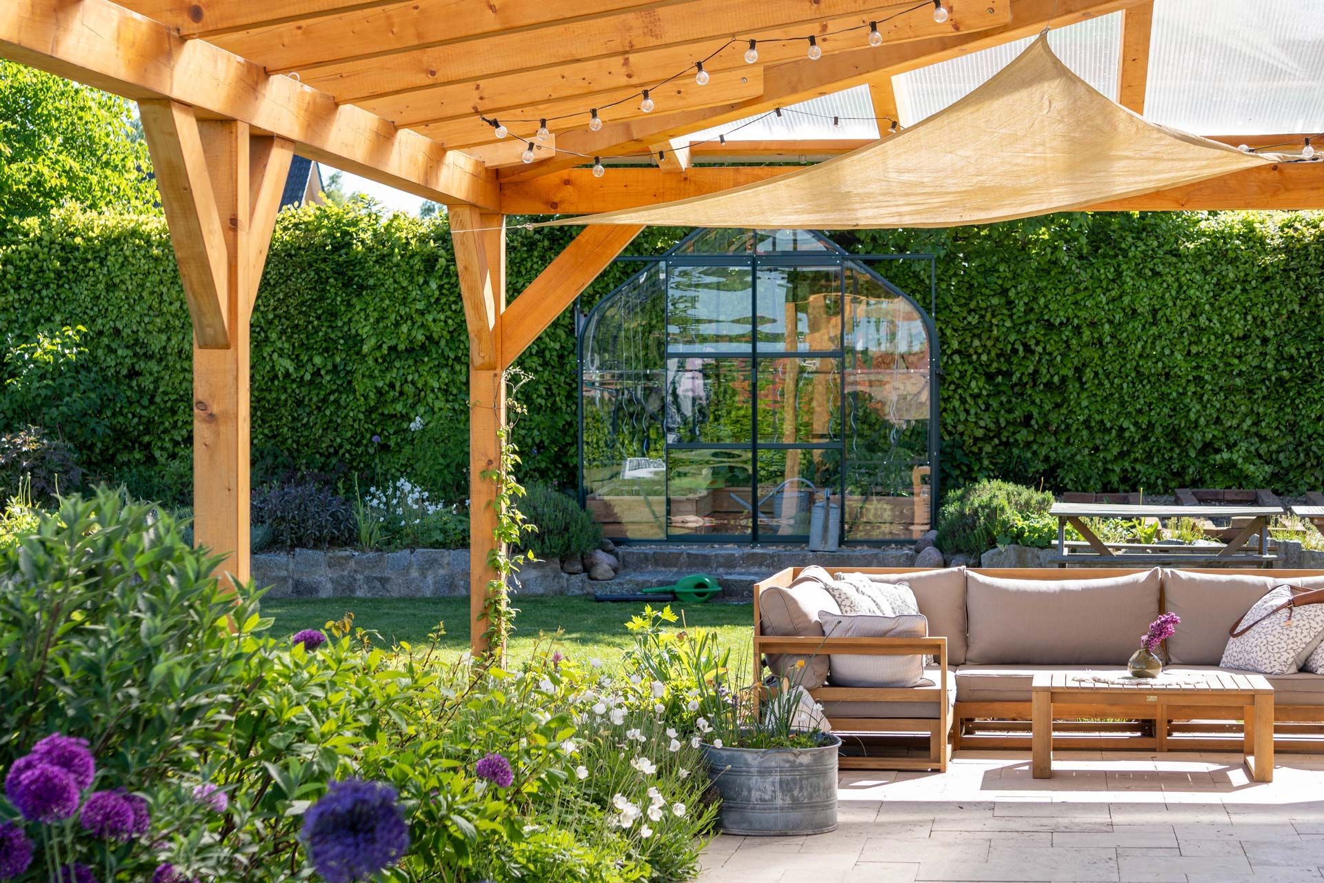 A sunny backyard with a wooden pergola over a patio