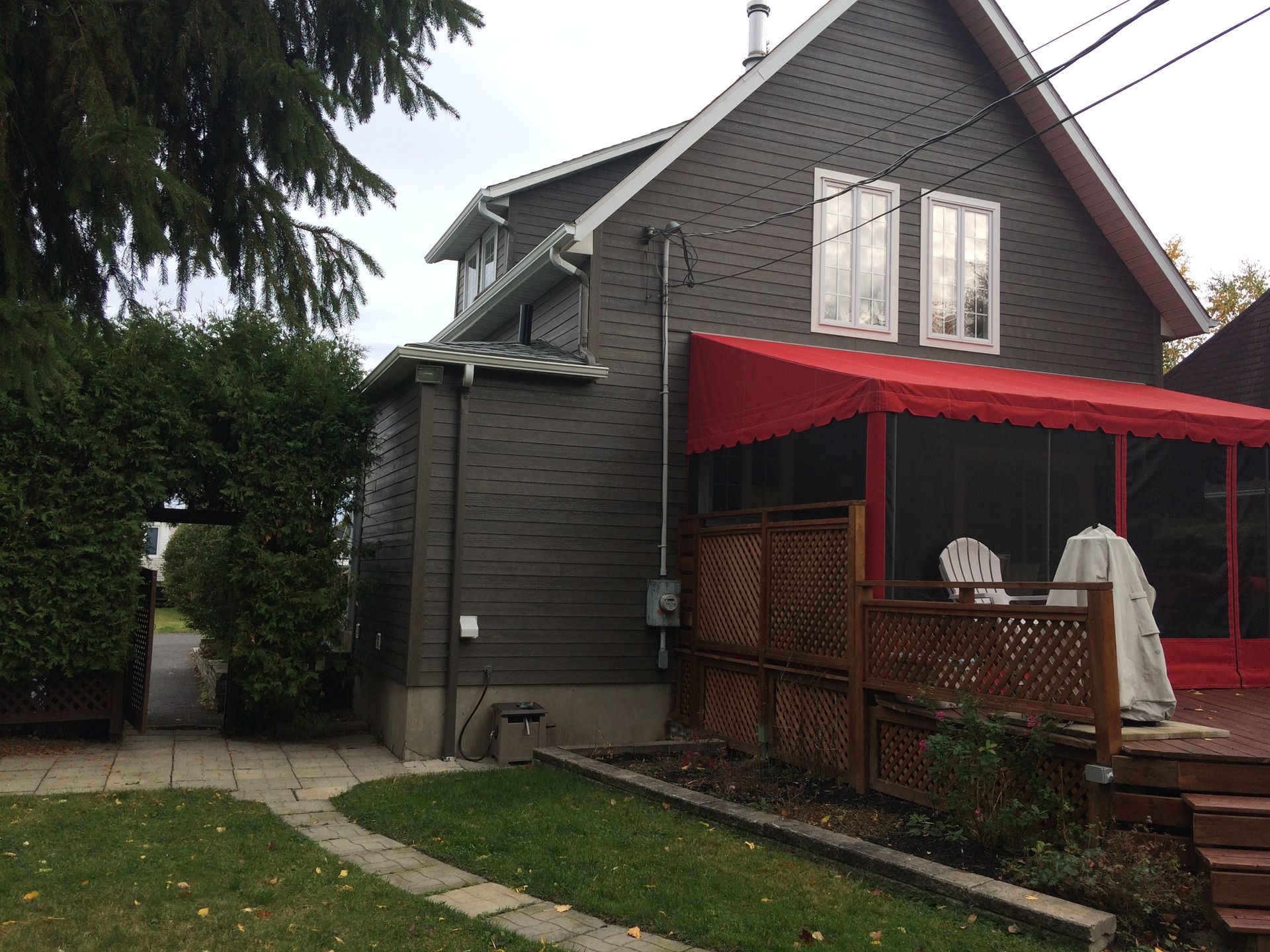 Une maison avec une véranda et un auvent rouge